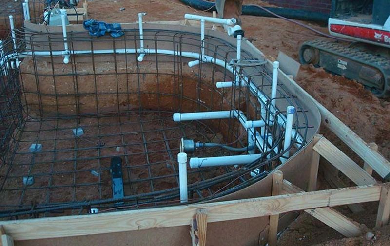Curved rebar cage and forms with embedded plumbing before shotcrete